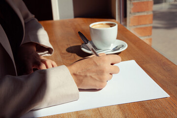 Mujer escribiendo en un folio. Mujer tomando café. Chica en cafetería. Escribiendo en cafetería. Mujer con folios.