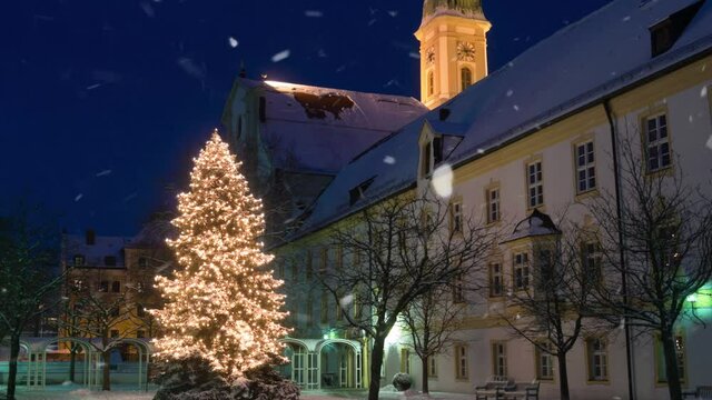 Beautiful christmas tree in front of church at blue hour with snow falling