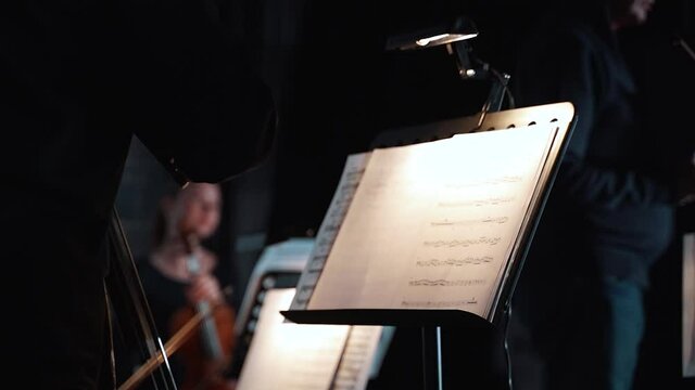 a girl flips a page of a music book before a performance in the theater