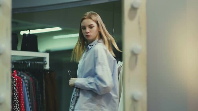 A pretty girl tries on clothes in the fitting room at a clothing store. Shopping