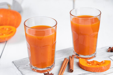 Two glasses of pumpkin juice on white wooden background. Vegetable detox drink for healthy diet.