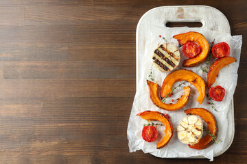 Board with baked pumpkin and spices on wooden background