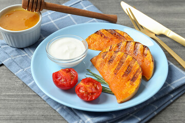 Concept of tasty eating with baked pumpkin on gray textured background