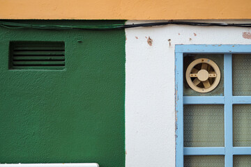 Colorful popcorn wall and a blue window with a vintage fan on it