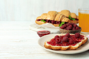 Concept of delicious food with croissants with raspberry jam on white wooden background