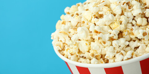 Paper cup with popcorn on blue background