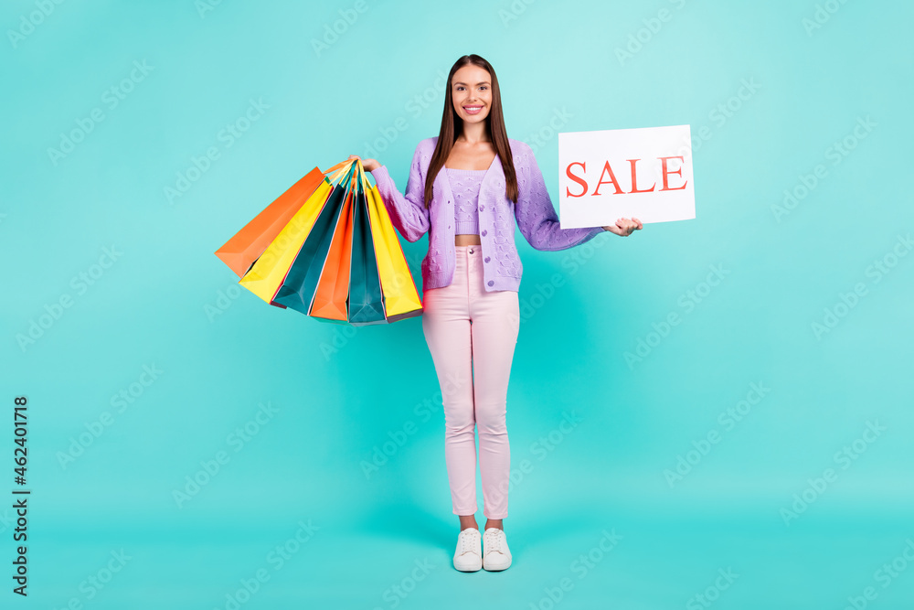 Poster Photo of cute sweet young woman dressed purple clothes holding shopping bags sale card smiling isolated teal color background