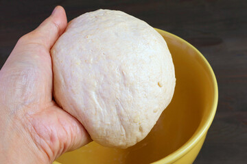 Hand putting kneaded dough in a bowl to let it rises before baking