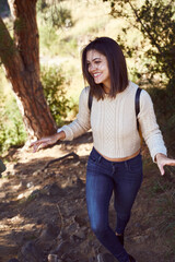 Cheerful young woman going hiking in the woods