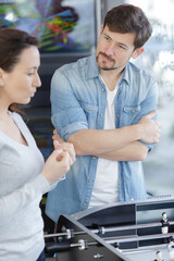 man and woman talking stood by table football game