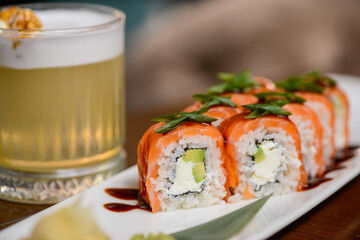 sushi roll philadelphia on a white long plate on a table with a cocktail close-up
