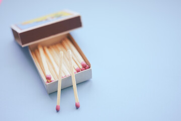 Matches in an open box on a pale blue paper table