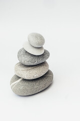 Fototapeta na wymiar Stone cairn on light background, stones tower, simple poise stones. Purity harmony and Balance Concept. Vertical photo.