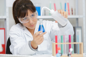 close-up of professional female scientist in protective eyeglasses making experiments