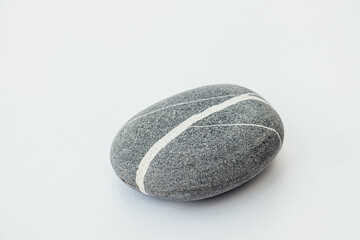 One sea stone of a round form on the light background. Top view of a smooth pebble.