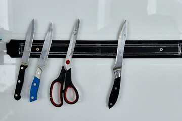 knives and scissors hanging on the wall on a magnetic holder