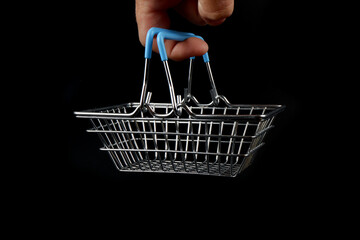 a small shopping basket hangs on a finger on a black background