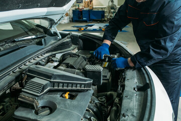 car service, an employee replaces and tests the car battery