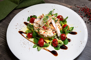 Salad with crab, cucumber, cocktail shrimp, avocado tartar and mango sauce. Large plate of food. Salad drizzled with olive oil, balsamic sauce.