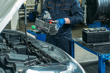 car service, an employee replaces and tests the car battery