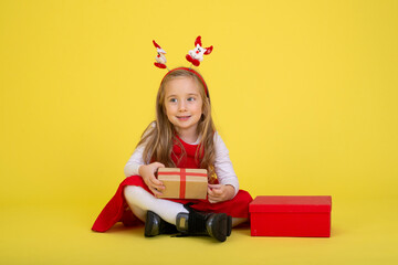 Portrait of happy little  girl Christmas  holding present box and looking at camera on yellow background