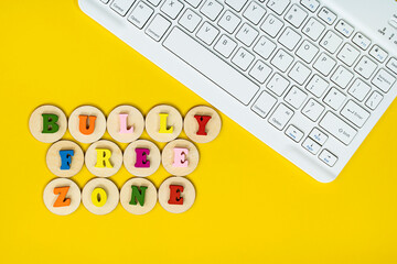 Layout of wooden alphabet on wooden tiles, keyboard with text BULLY FREE ZONE. Cyberbullying concept