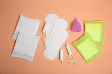 Menstrual pads and other period products on pale orange background, flat lay