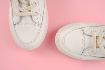 Casual comfortable white shoes.Stylish women's leather sports sneakers with laces on a pink...