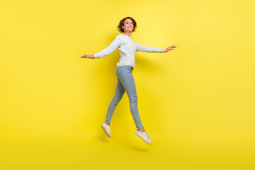 Fototapeta na wymiar Photo of inspired lady jump move go wear blue pullover jeans footwear isolated yellow color background