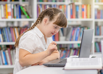 Girl with special needs uses a laptop at school