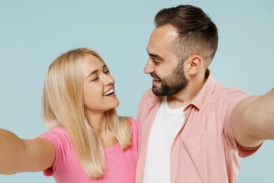 Close up young fun couple two friends family man woman in casual clothes doing selfie shot pov on mobile phone look to each other together isolated on pastel plain light blue color background studio.