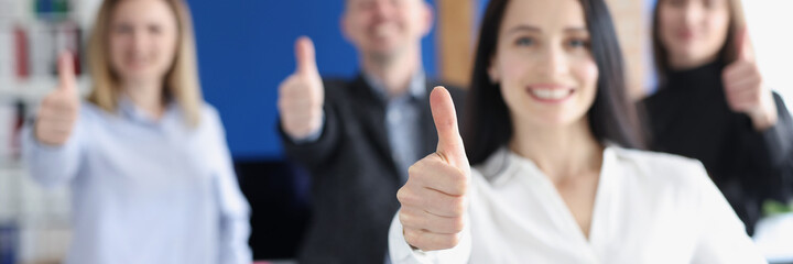 Business leaders with group of employees showing thumbs up