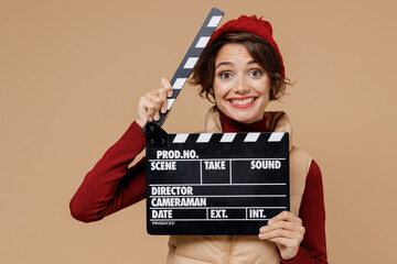 Young cheerful smiling happy woman 20s in red turtleneck vest beret holding classic black film...