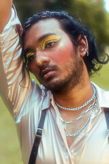 dreamy portrait of a dark skinned Indian man in Malaysia, with make up, in a field, surrounded by...