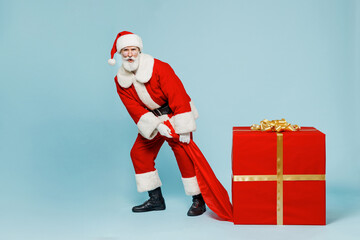 Full body old Santa Claus man 50s in Christmas hat red suit clothes pull heavy gift present box isolated on plain blue background studio Happy New Year 2022 celebration merry ho x-mas holiday concept