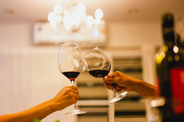Couple making a toast with glasses of red wine at dinner party.