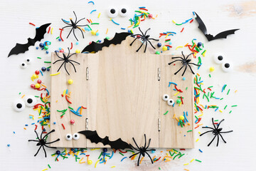 holidays image of Halloween. spiders, bats and wooden board frame for text or mock up over white table
