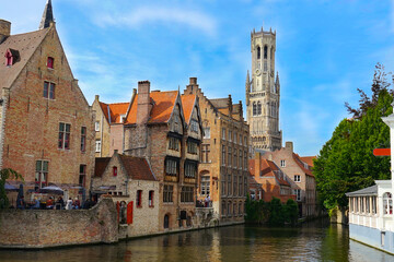 Fototapeta na wymiar view of the famous dijver canal with historic buildings alongside the watercourse and view of the belfry tower in the center of bruges, Flanders, belgium