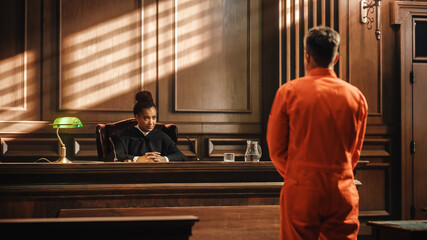Court of Law and Justice Trial Proceedings: Law Offender in Orange Jumpsuit is Questioned and Giving Testimony to Judge, Jury. Criminal Denying Charges, Pleading, Inmate Denied Parole. - obrazy, fototapety, plakaty