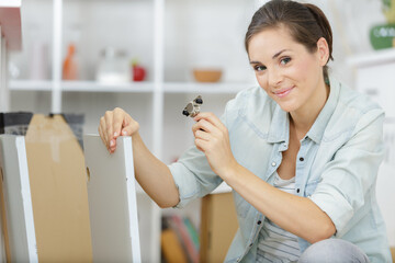 young woman assembling furniture in new apartment