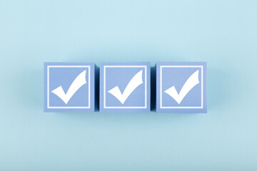 Three white checkmarks on blue cubes against bright pastel blue background