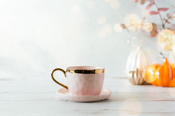 Details of Still life, cup of tea or coffee, pumpkins, candle, brunch with leaves on white table background, home decor in a cozy house. Autumn weekend concept. Fallen leaves and home decoration