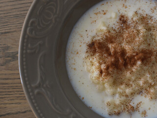 Riceporridge with milk and cinnamon in a plate with nice pattern. 