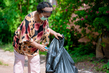 Senior woman picking up plastic bottle, garbage collecting in a forest cleaning planet. environment protection pollution problems and global warming, plastic waste caring about nature concept.