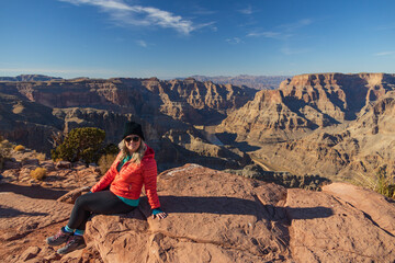 Smiling girl sitting on rock overlooking the Grand Canyon, Arizona, USA
