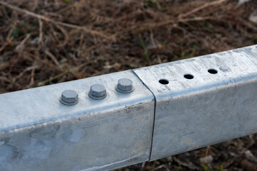 Three bolts and three holes on connected galvanized metal profiles