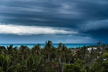 Fototapeta na wymiar Dramatic storm clouds over the sea, forest and rooftops on a summer day