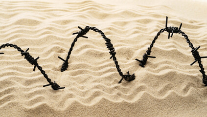 A piece of barbed wire lies on the sand.