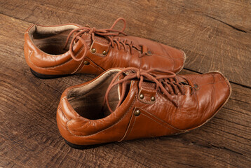 Mens brown old shoes on a dark wooden background.