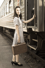 A young woman in retro vintage style with a brown retro suitcase enters her train carriage. Traveling by train.